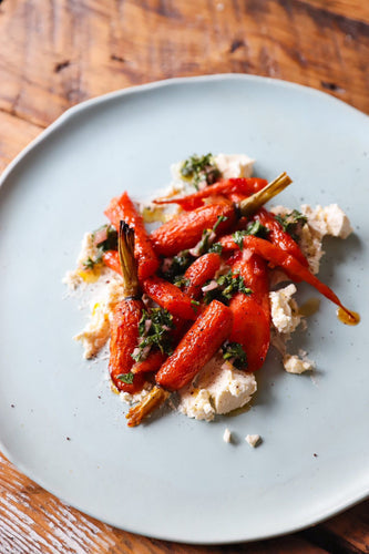 roasted carrots over soft cheese on a white plate